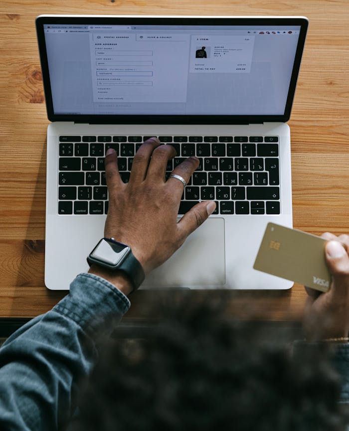 Home Person using a laptop to make an online purchase with a credit card on a wooden table.